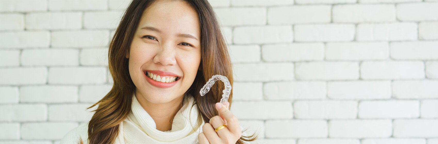 Smiling woman holding invisalign aligners